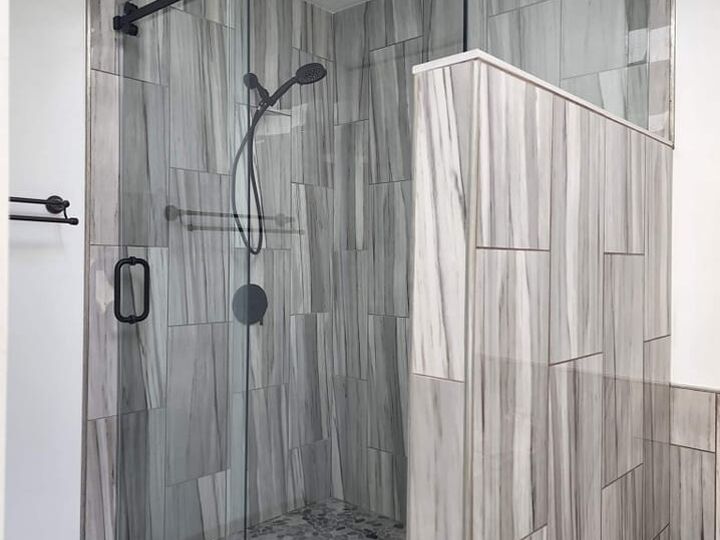 Sliding glass shower enclosure with dark hardware